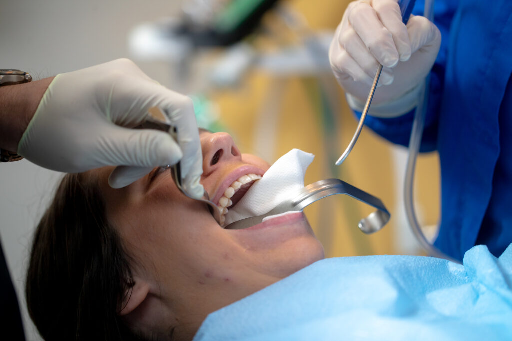 woman undergoing oral surgery with tools in her mouth